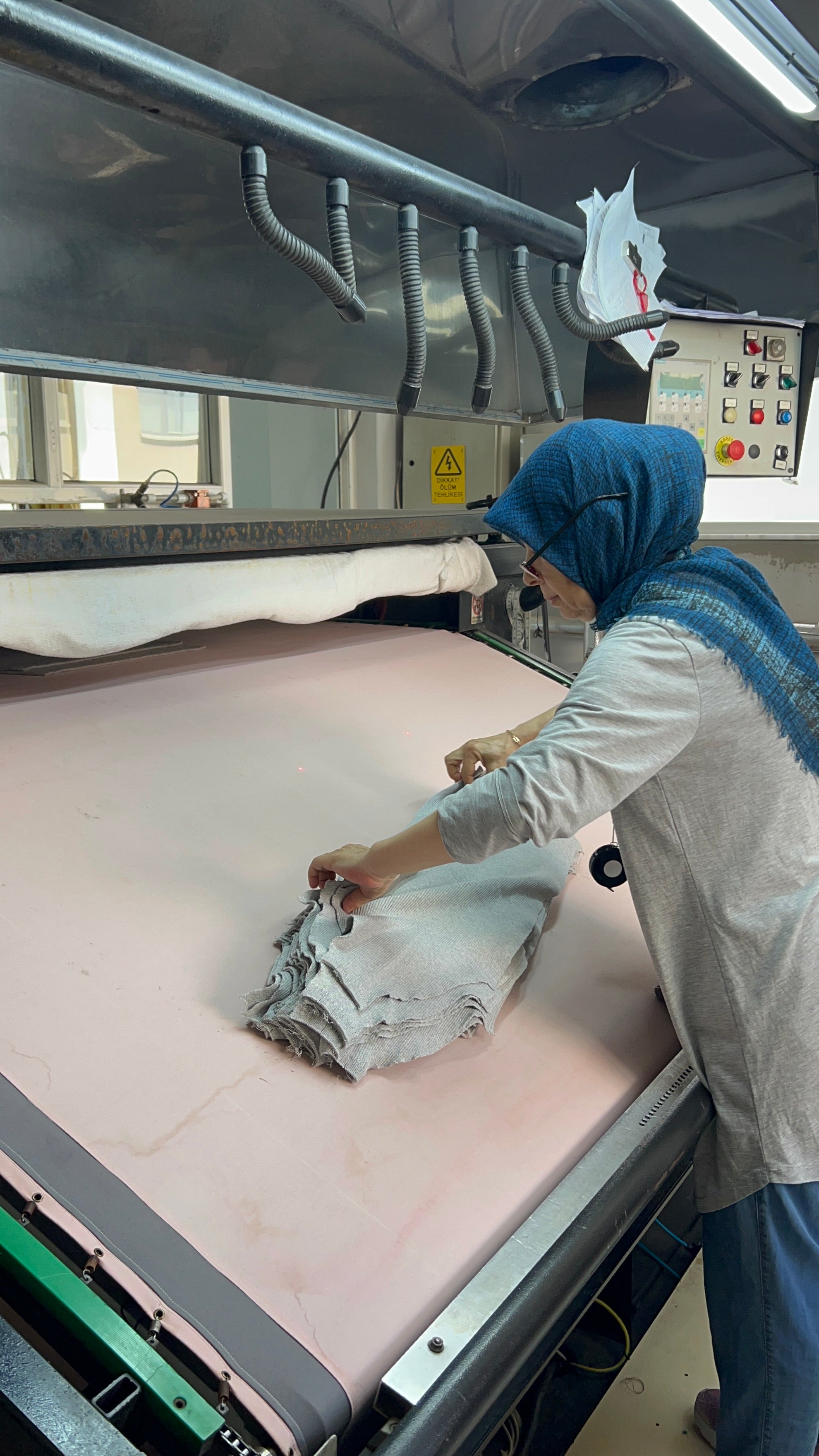 Woman with glasses and hijab inspecting knitwear for knitting mistakes.